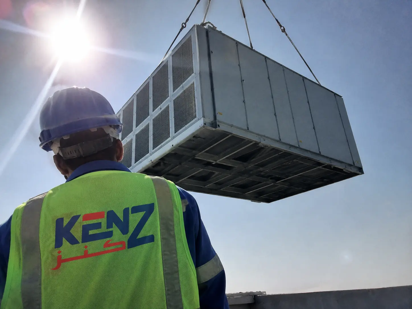 Massive packaged rooftop HVAC unit suspended mid-air by heavy crane rigging