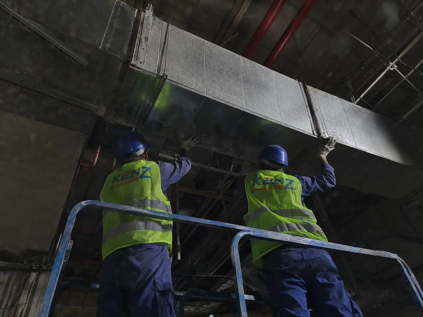 Kenz technicians on scissor lift installing high-elevation HVAC ductwork