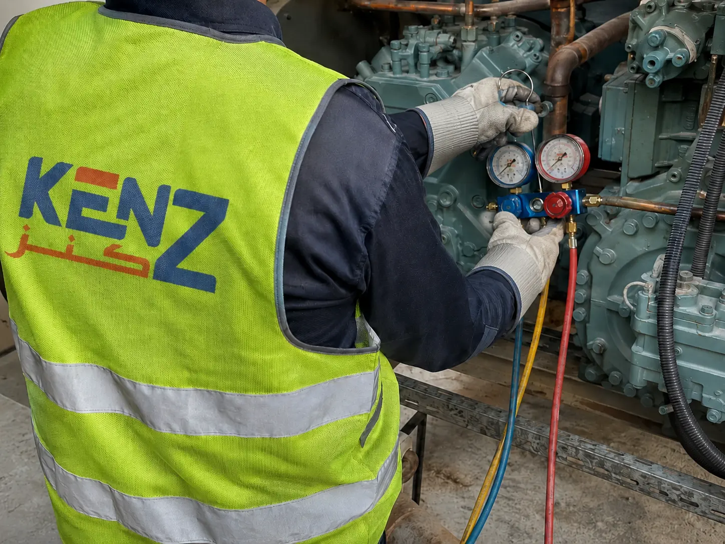 HVAC technician connecting diagnostic manifold gauges to industrial compressor