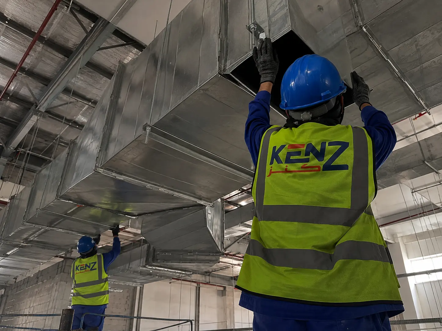Kenz technicians installing massive galvanized steel HVAC ventilation ducts