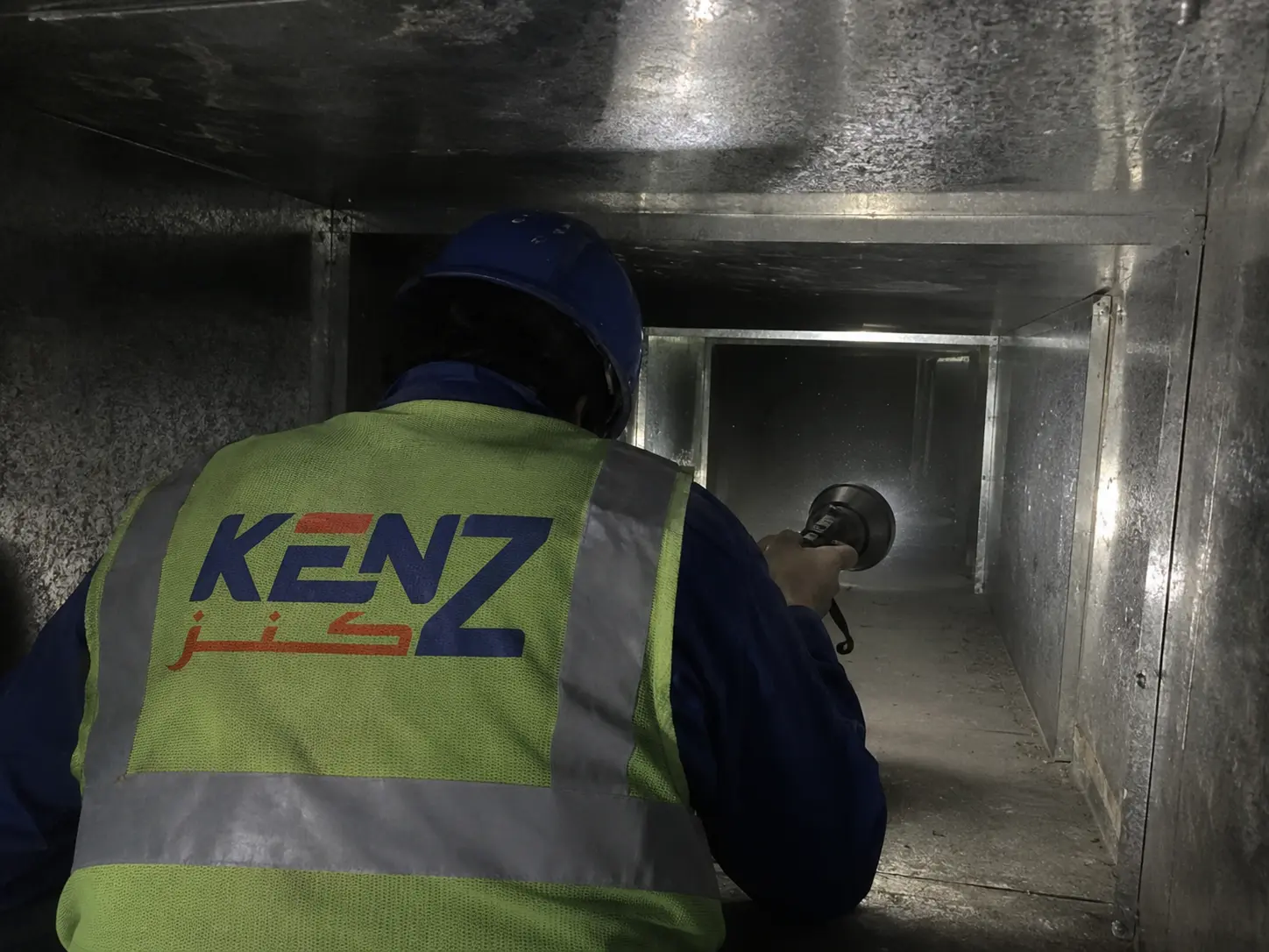 Technician using flashlight to inspect industrial utility trench and galvanized steel enclosures