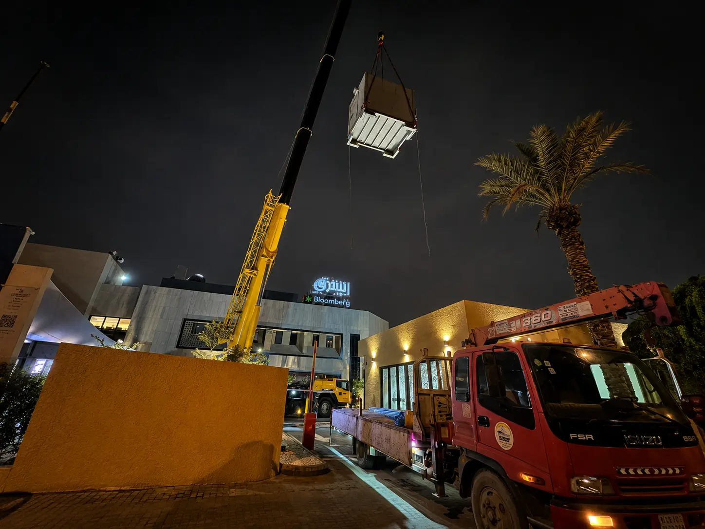 Heavy crane lifting Kenz prefabricated equipment shelter at night for Al Arabia in the Diplomatic Quarters, Riyadh