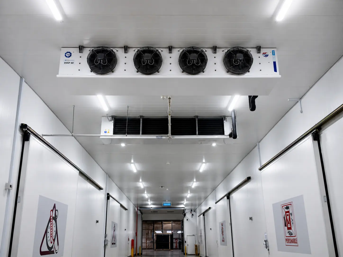 Ceiling Evaporators: Long corridor view showing large industrial ceiling-mounted evaporator fans inside commercial cold room