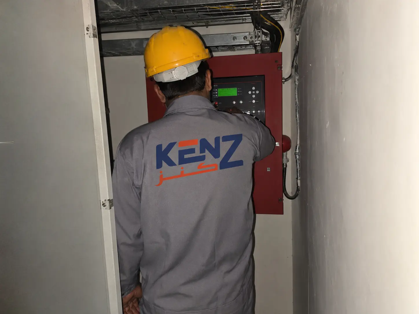 Kenz technician inspecting automated fire safety panel inside telecom shelter